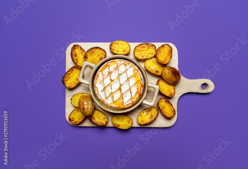 Baked camembert with roasted potatoes on a purple background