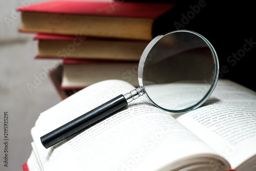 Magnifying glass rests on open book, concept of learning and discovery process.