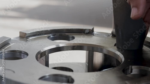 Mechanic polishing planetary gear carrier pin bore using sandpaper inside workshop.