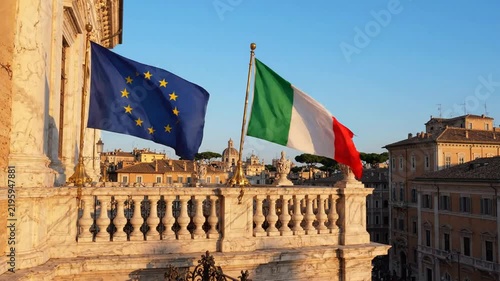 European union and italian flags waving together over rome cityscape at sunset italy