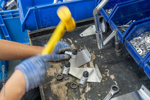 Workers assembling metal hardware connectors hammering with mallets