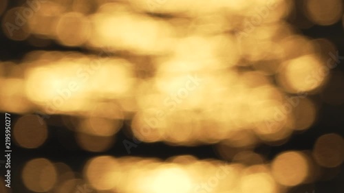 blurry, yellowish-orange sunset over water. The water appears to be rippling and the sky is filled with a warm, golden glow.