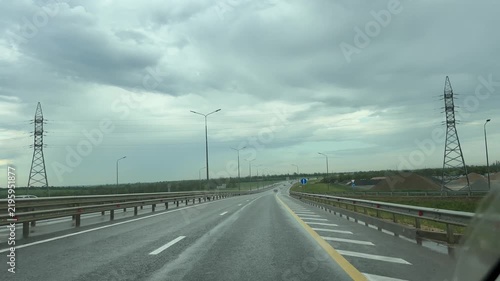 Asphalt highway road stretches toward the distant horizon under overcast skies. Point of view driving shot.