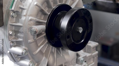 Panning shot of shiny transmission output flange mounted on cast aluminum housing.