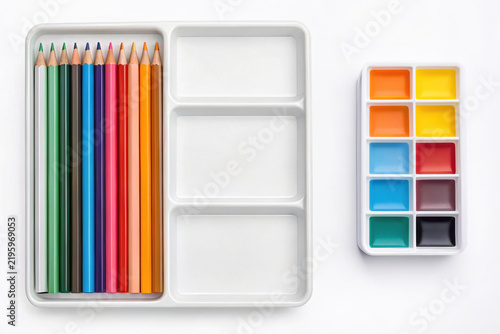 Colorful pencil tray with bright colored pencils and paint palette isolated on white background. The pencil tray showcases vibrant colors in organized compartments