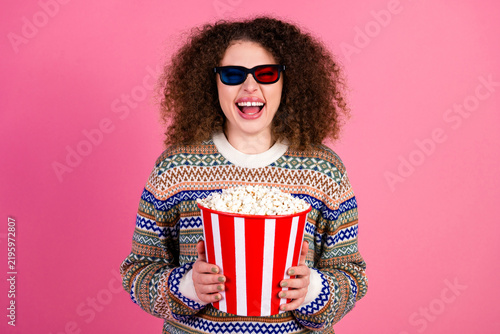 Fotografie Happy young woman in 3D glasses holding a large popcorn bucket for movie night a
