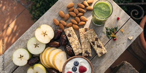 Healthy breakfast spread with fruit, nuts, energy bars, and green smoothie