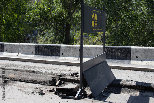Bild auf Leinwand Damaged asphalt and temporary construction barrier on a road during maintenance and repair work