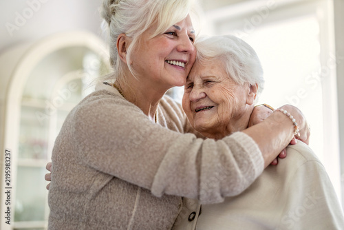 Happy senior woman and her adult daughter at home
