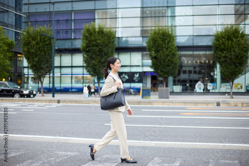 都市の歩道を歩くビジネスウーマンの全身