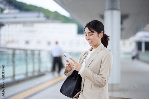 Obraz na płótnie 駅の連絡通路でスマートフォンを操作するビジネスウーマン