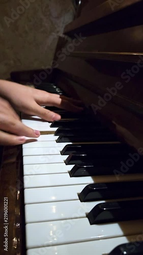 Close-up of female fingers playing on black and white piano keys in a music studio background