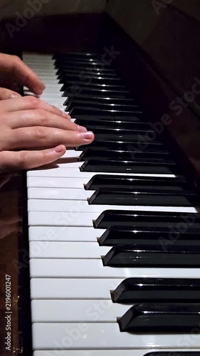 Close-up of female fingers playing on black and white piano keys in a music studio background