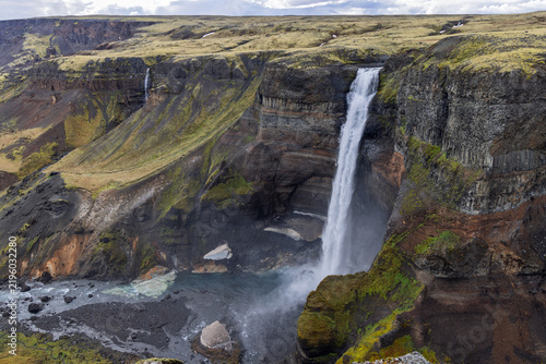 Fotografie Haifoss waterfall plunges beside layered cliffs in Thjorsardalur, Iceland, sending spray across the Fossa River below