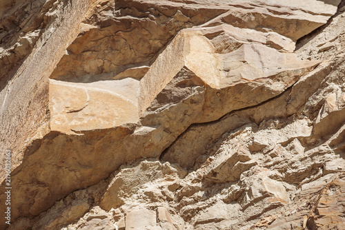 Fotografía Detailed view of sharp, layered geological sandstone rock strata and rugged cliff face showing natural erosion and angular fractures in bright sunlight