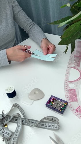 Vertical video. A novice seamstress, tailor, woman cuts a small skirt pattern with scissors. Learning to sew at home, developing creative skills
