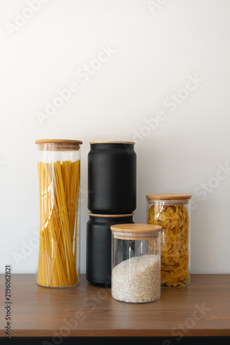 Glass food storage jars on kitchen counter, vertical. Tidy minimalist home