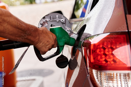 Hand refueling car at gas station with rising fuel prices