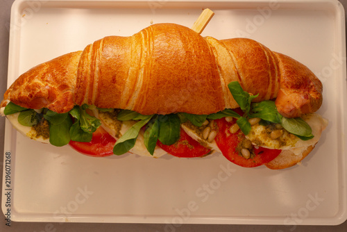 Obraz na plátne golden flaky croissant sandwich filled with fresh mozzarella slices, ripe tomato