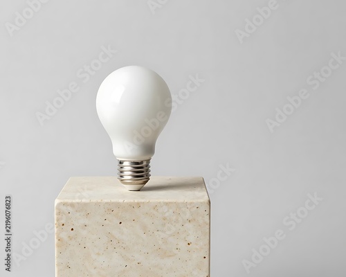 White light bulb standing on marble pedestal with copy space