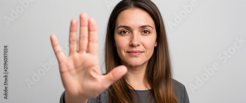A woman standing with her hand open facing the camera to say no