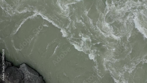 Aerial drone footage a powerful flow of gray green water in a mountain river rushing among rocky banks. A harbinger of the spring flood.