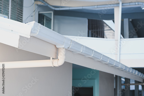 White plastic rain gutter system installed on building roof.