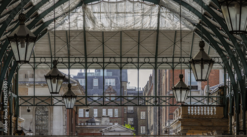 Architecture greco-roman style with iron glass roof and Lanterns hanging on the ceiling in Covent Garden Market Hall. View of Metallic framework arch roof with ceiling hanging lamp.
