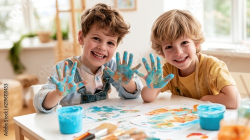 Two cheerful young boys with colorful paint-covered hands enjoying a fun art activity at home, expressing creativity and joy in an engaging environment