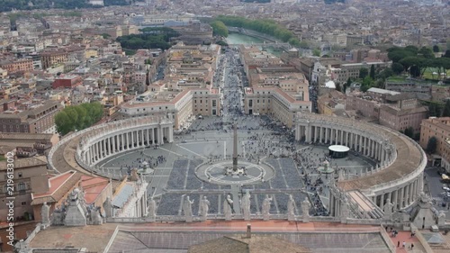 A massive crowd visits the majestic St Peters Square and its iconic colonnade under a bright sky. Historic religious monuments inspire deep spiritual faith and global cultural unity.