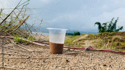 Obraz na plátne Discarded plastic cup with coffee residue left on the ground in nature