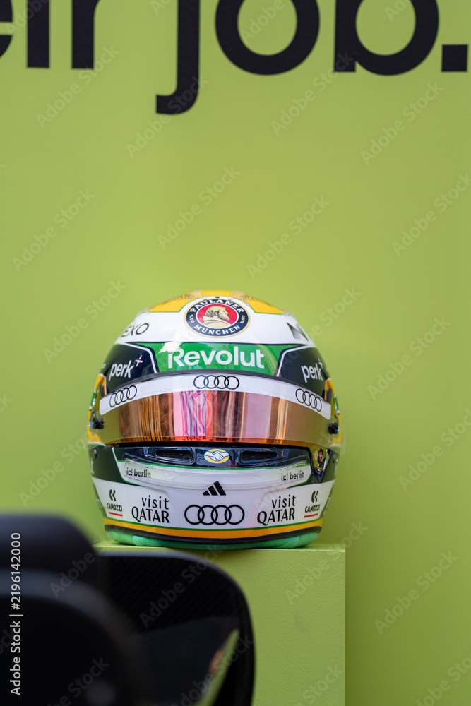 Obraz premium NEW YORK, USA – SEPTEMBER 16, 2026: a Formula 1 racing helmet on a green display background with sponsor logos and reflective visor.