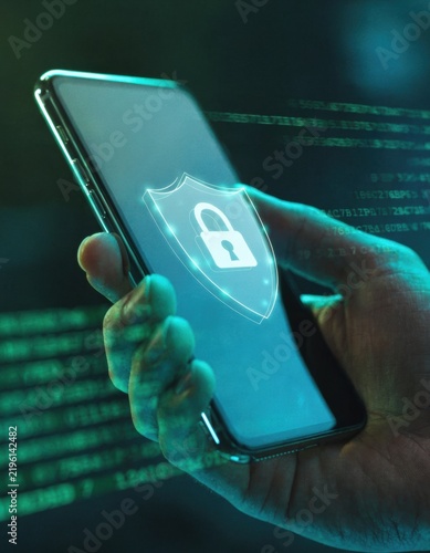 Hand holding smartphone with glowing padlock shield and digital code