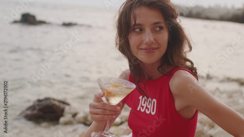 Enjoying a drink by the sea at sunset with friends in 1990-style attire