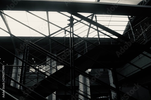 Fotografía A low angle vertical abstract photograph of a massive modern building glass roof with black metal steel beams creating a stark geometric pattern against the light