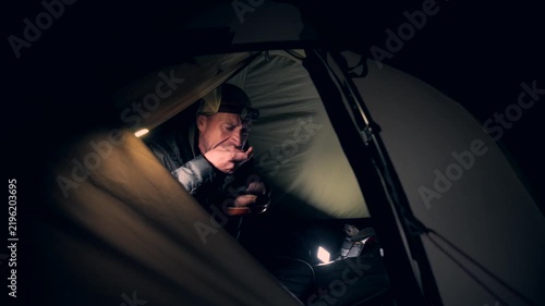 A man eating food in a tent at night