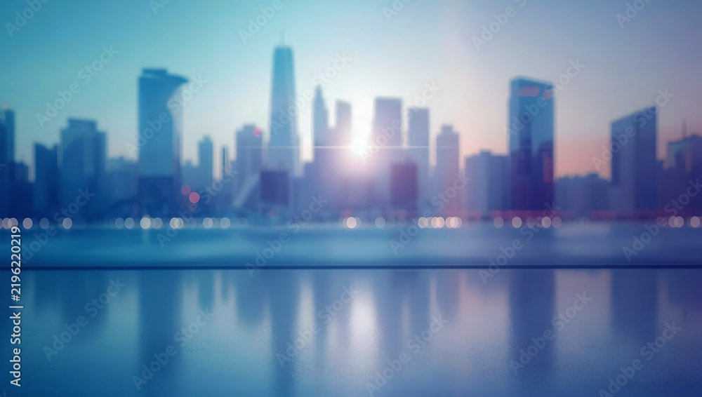 Fototapeta premium Blurred City Skyline At Sunset With Reflection On Surface And Bright Lens Flare In Blue And Orange