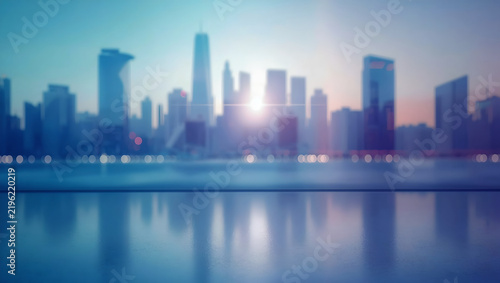 Blurred City Skyline At Sunset With Reflection On Surface And Bright Lens Flare In Blue And Orange