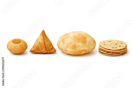 Assorted traditional indian snacks like crispy puri fried samosa fluffy bhatura and unleavened flatbread papad stacked for authentic culinary food photography.