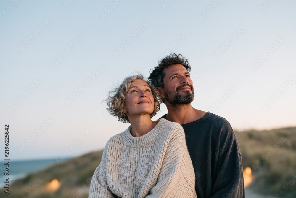 Naklejka premium Romantic mature couple gazing at sunset by the sea for lifestyle background and romantic banner design