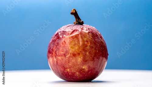 A single fresh passion fruit resting on a white surface against a blue background.