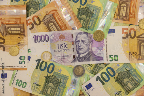 Czech koruna and euro banknotes arranged together as physical paper currencies, displaying the distinctive colors, denominations, portraits, architectural motifs, national symbols