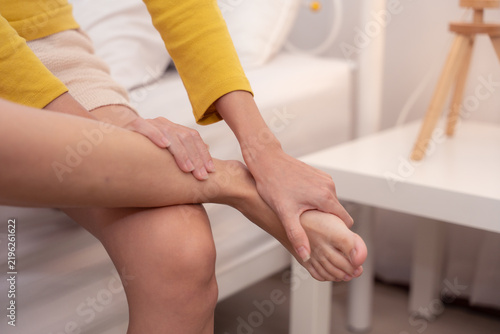 Canvastavla Woman holding her heel and arch in pain, indicating plantar fasciitis, foot fatigue, or heel inflammation from prolonged standing or walking