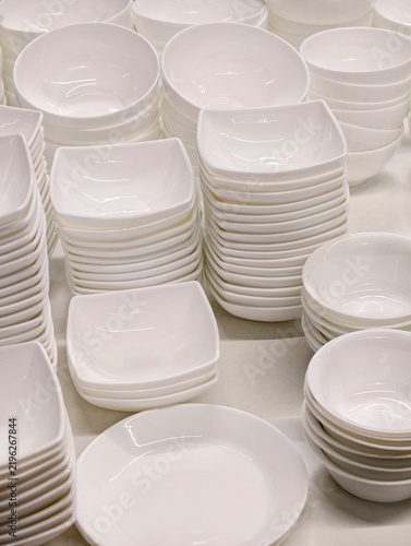 Bild auf Leinwand Ceramic white tableware arranged in stacked sets including plates saucers and sa