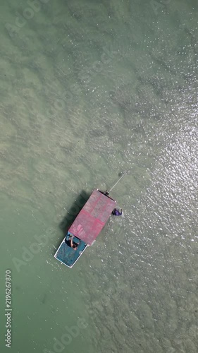 Vista aérea direta de barco colorido ancorado em água cristalina rasa, composição vibrante durante passeio de barco pela Rota Ecológica dos Milagres