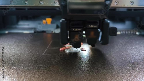 A close‑up of a 3D printer extruder during layer‑by‑layer printing of a small item on the work platform.
