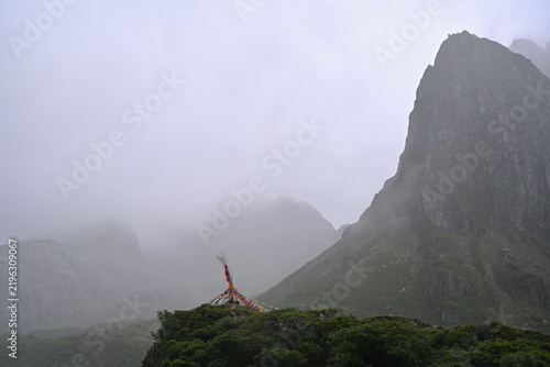 Colorful Tibetan Prayer Flags and Dramatic Misty Mountain Peaks in Abujicuo, China