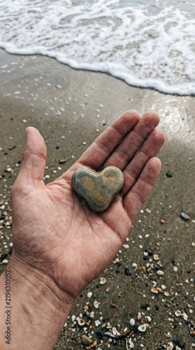 Heart shaped stone in hand on beach