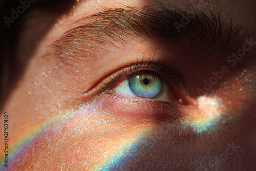 Macro eye close up blue green iris reflecting sunlight prism on male skin with glittering texture emotional curiosity