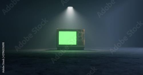 Vintage television with green screen display flickering on under top spotlight in dark room with subtle camera shake